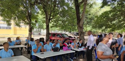 Estudiantes tomando clases bajo árboles.