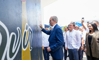 El presidente Luis Abinader firma un mural realizado por el artista Angurria durante la inauguración del nuevo edificio del Instituto Policial de Educación Superior (IPES).