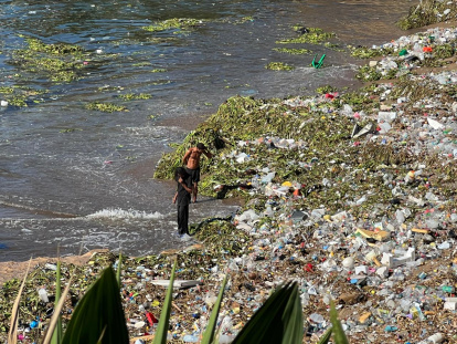 Dos hombres buscan cosas de valor entre la densa capa de plástico, lilas y basura que cubre la orilla del litoral marino de la playa del Fuerte de San Gil en el mar Caribe. Jorge González