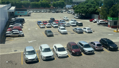 En esta fotografía se identifican unos 58 vehículos  de los cuales 26 son de color blanco, lo que representa aproximadamente el 45% del total del parqueo. Jorge González