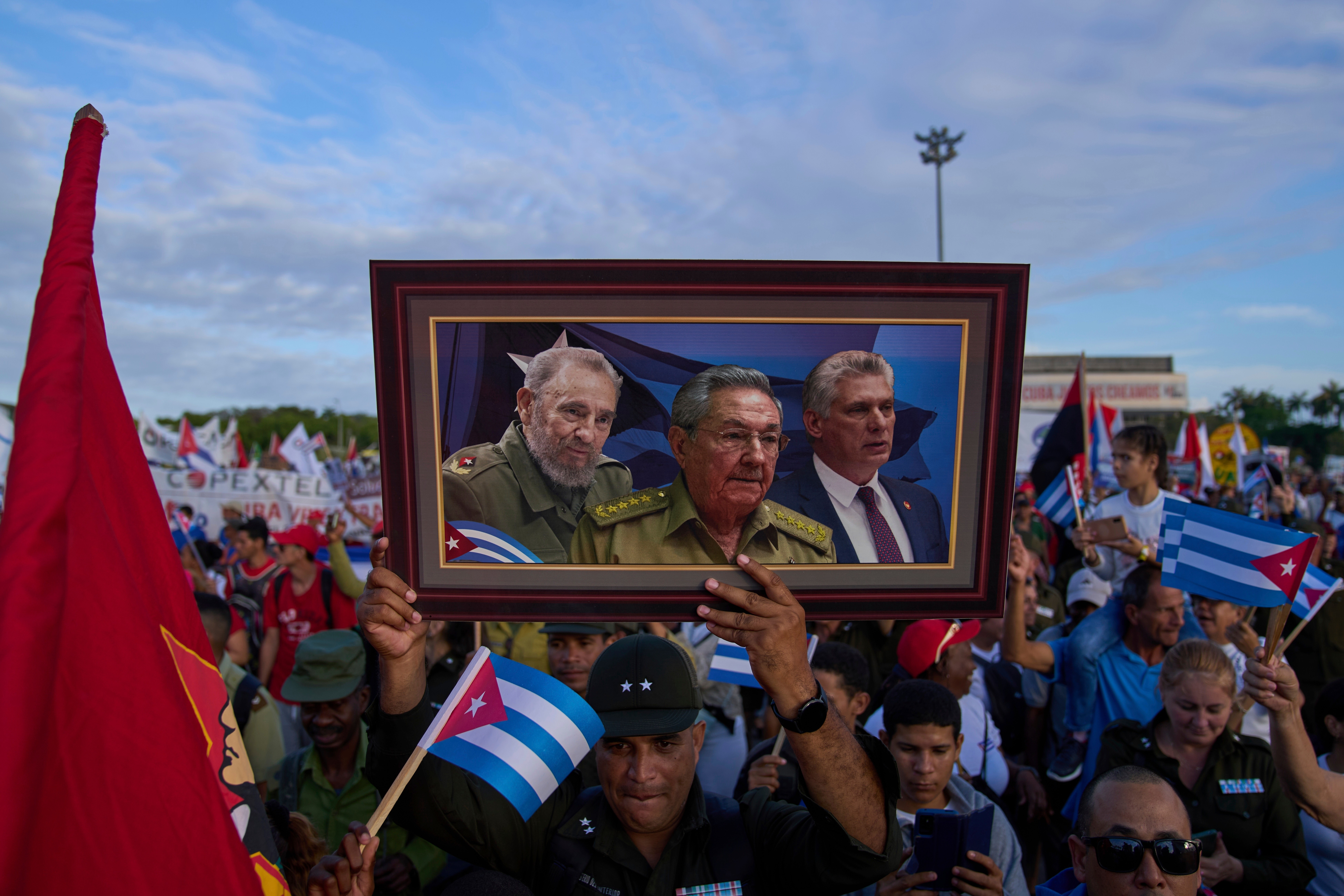 ARCHIVO - Un manifestante sostiene una imagen compuesta enmarcada de Fidel Castro, Raúl Castro y el presidente de Cuba, Miguel Díaz-Canel, durante el desfile del Primero de Mayo en la Plaza de la Revolución en La Habana, el 1 de mayo de 2025. (Foto AP/Ramon Espinosa, Archivo)