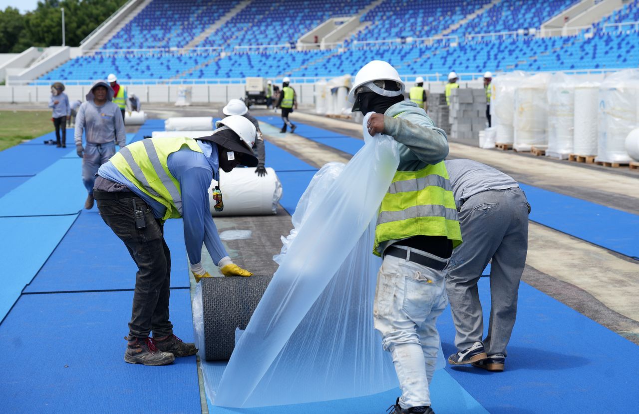 Trabajadores instalan material sintético para la nueva pista de atletismo del Estadio Félix Sánchez