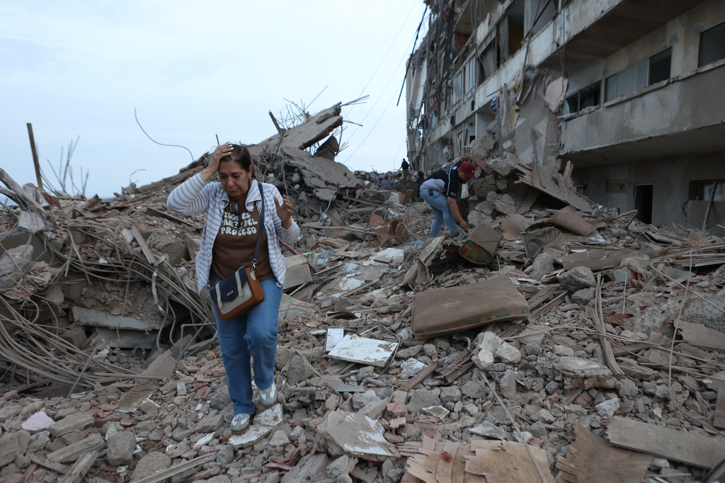 Varios vecinos caminan entre los escombros de edificios dañados por el terremoto que sacudió el día anterior en Catia La Mar, Venezuela, el jueves 25 de junio de 2026. (AP).