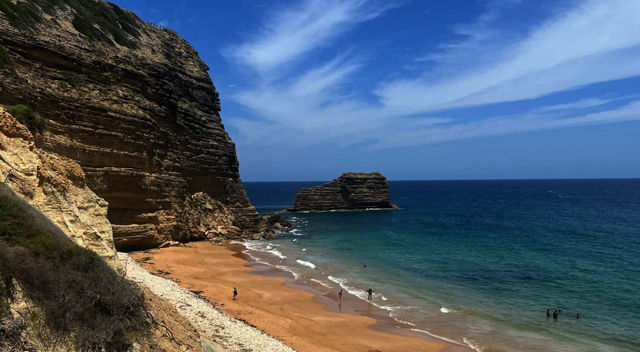 Playa del Morro, que muestra la icónica formación rocosa 'El Morrito' (con forma de zapato) en primer plano. El cielo y el mar se funden en un impresionante y perfecto cambio de gradiente, desde el azul turquesa cristalino del agua al azul profundo del mar y al celeste del cielo. Luz natural brillante del mediodía, ultra detallada, calidad 8k, estilo cinematográfico y real." Jorge González