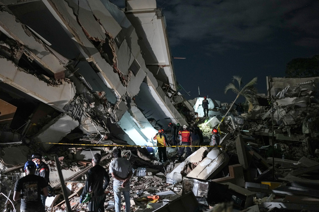 Los rescatistas buscan entre los escombros de un edificio que se derrumbó durante un terremoto en La Guaira, Venezuela.