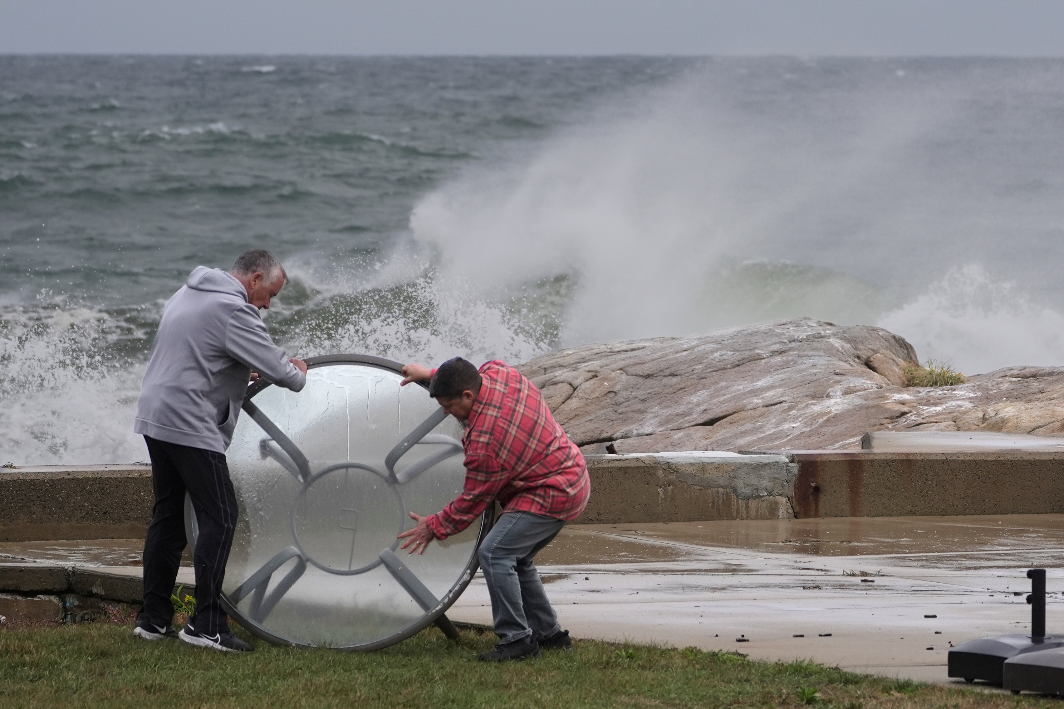 John Garrisi, izquierda, y Gaige Graf retiran una mesa de exterior de la zona costera durante las primeras fases de una tormenta del noreste, el viernes 25 de septiembre de 2026, en Gloucester, Massachusetts. (AP Foto/Robert F. Bukaty)