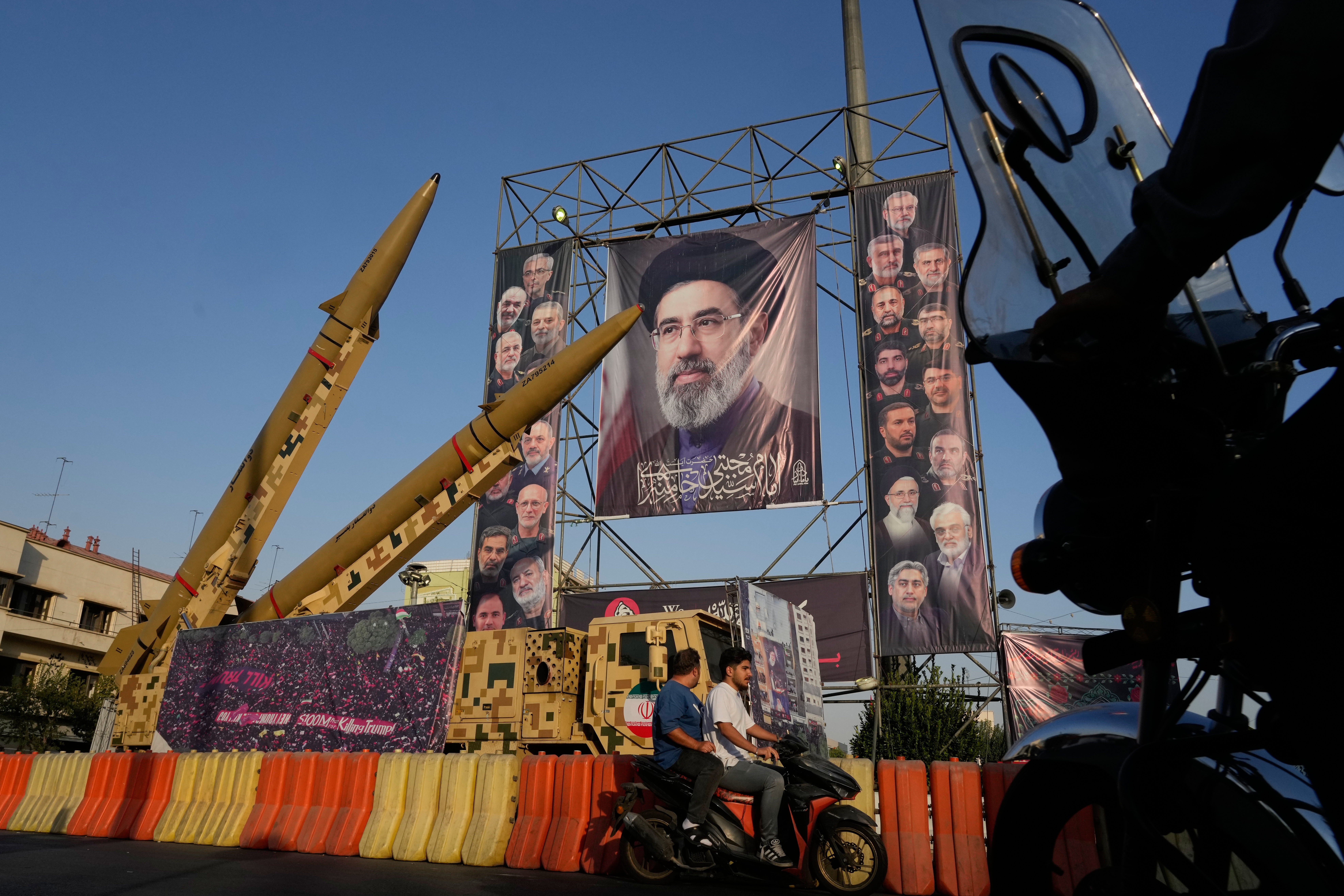 Motocicletas pasa junto a misiles y carteles iraníes con la imagen del líder supremo de Irán, el ayatolá Moytabá Jamenei, en el centro, y comandantes militares y científicos nucleares que murieron en ataques israelíes y de EEUU, mostrados en una exhibición militar por el aniversario del inicio de la guerra entre Irán e Irak entre 1980 y 1988 en la plaza de Baharestan, en Teherán, el lunes 28 de septiembre de 2026. (AP Foto/Vahid Salemi)