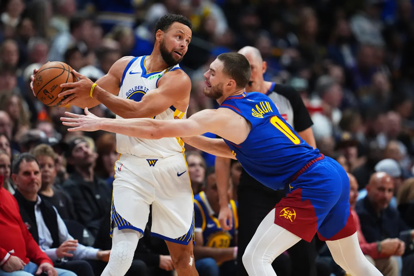 Stephen Curry, base de los Golden State Warriors, busca pasar el balón ante la presión de Christian Braun, durante la primera mitad del partido.