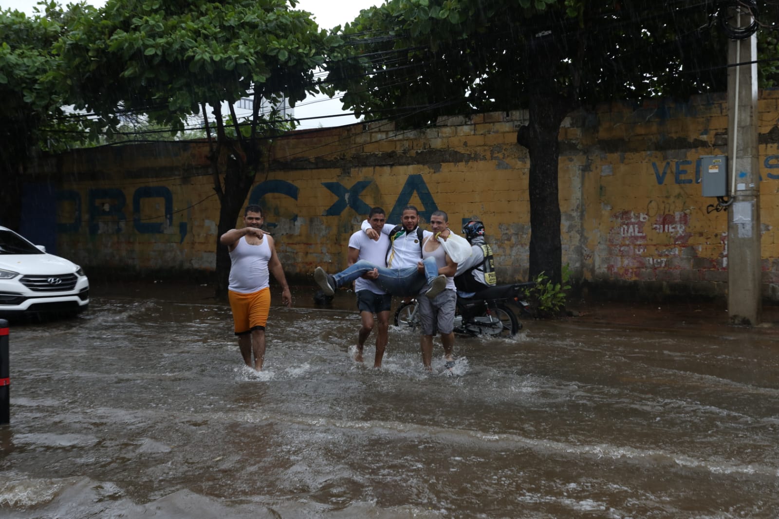 Jóvenes cruzan una calle inundada en Santo Domingo
